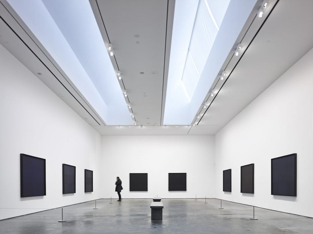 monochromatic black modern paintings hang on the wall of an art gallery 