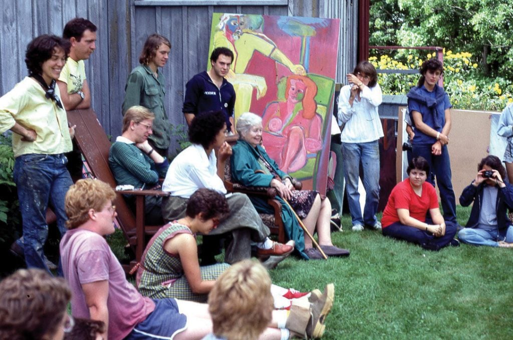 students sitting and listening to an artist talk outside