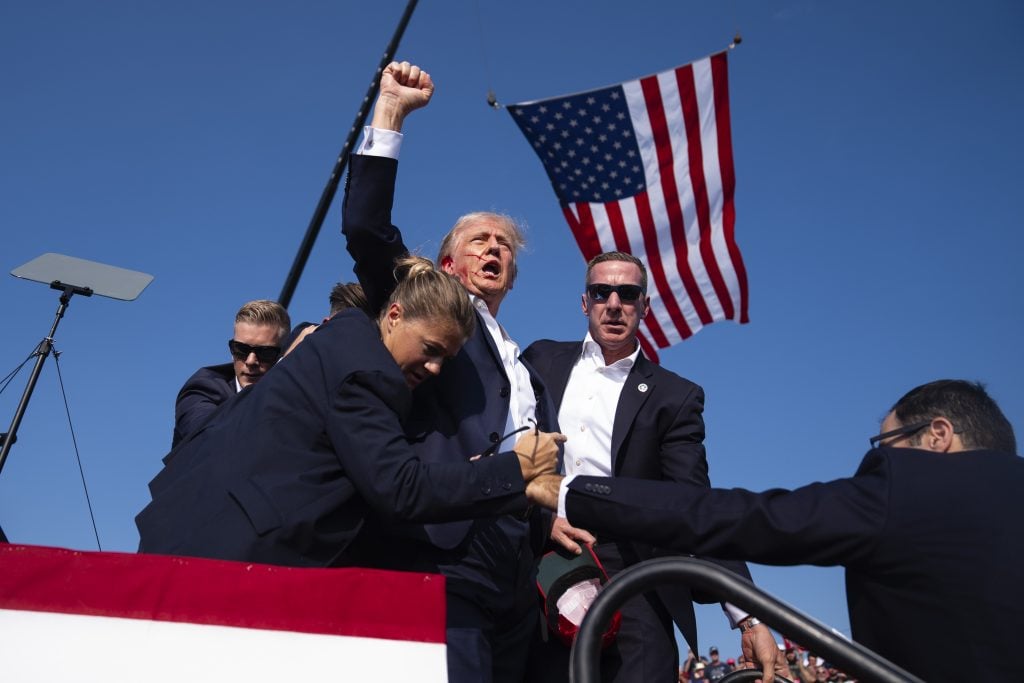 a man holds up a fist in front of an american flag