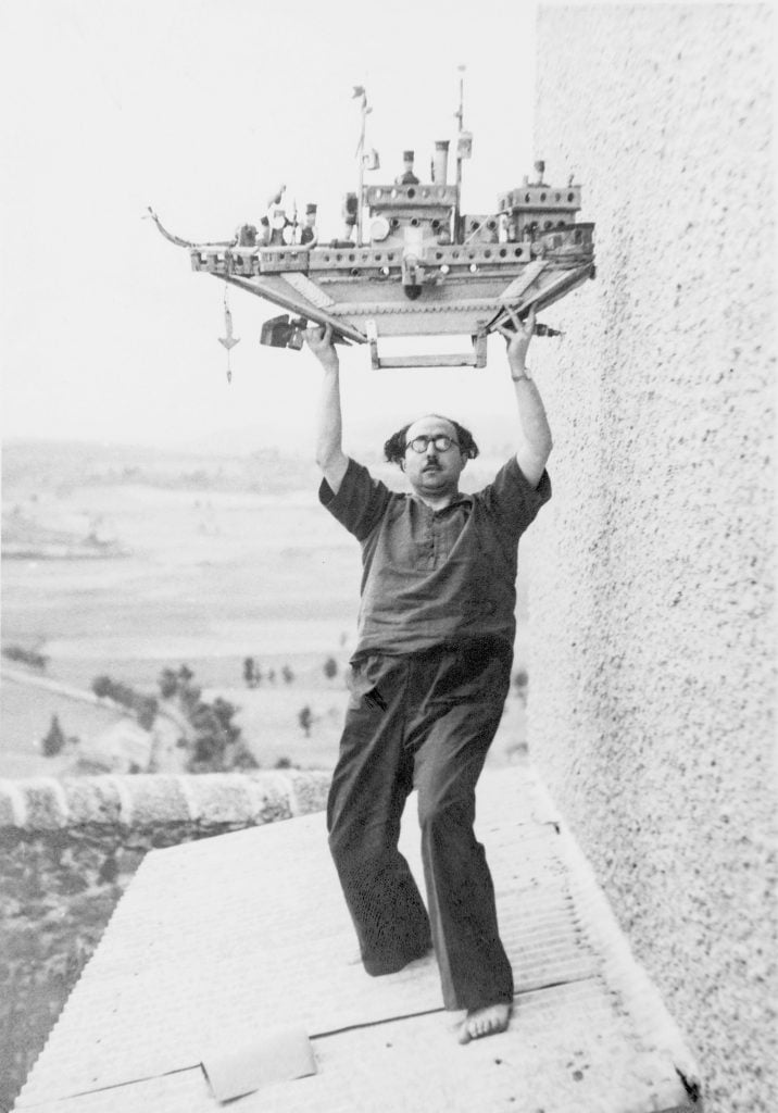 Francesc Tosquelles on the Roof of a Building at the Saint-Alban Psychiatric Hospital, Holding an art brut sculpture by Auguste Forestier