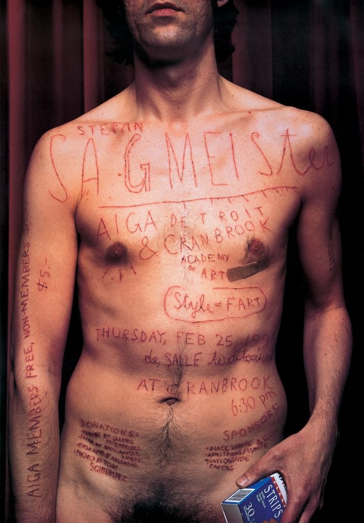 An image of a man standing shirtless with text etched into his skin, promoting a design event. The text includes the name "Stefan Sagmeister," the date "Thursday, Feb 25, 1999," and details about the event organized by AIGA Detroit & Cranbrook Academy of Art. The text appears to be etched or scratched into the skin, creating a striking and provocative visual. The man holds a box labeled "Strips" in his right hand.