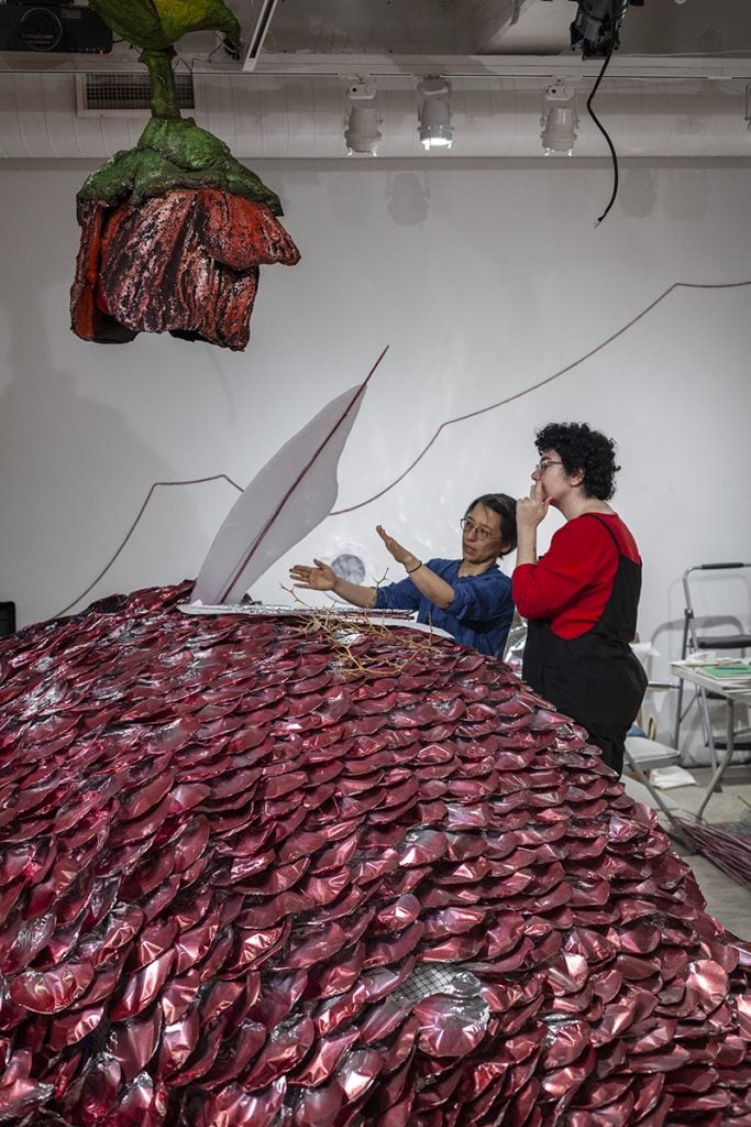 Director of Studio Operations, Nami Yamamoto (at left), discusses plans for the fin of a red snapper sculpture with Project assistant Hannah Moog. The sculpture serves as the centerpiece of the exhibition’s largest room . John Jarboe , in collaboration with The Fabric Workshop and Museum, Philadelphia. The Rose Garden , 2024. Photo credit: Carlos Avendaño