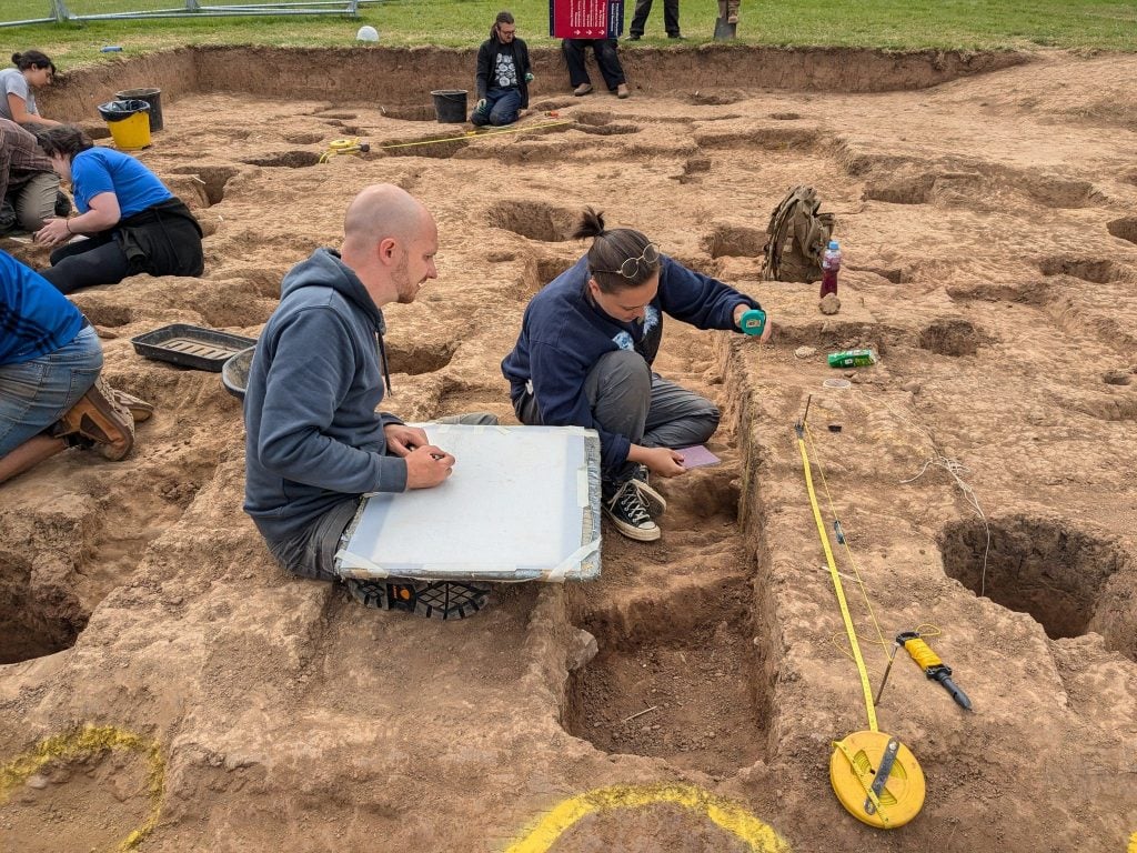 a man and woman are seen measuring holes being dug in a field