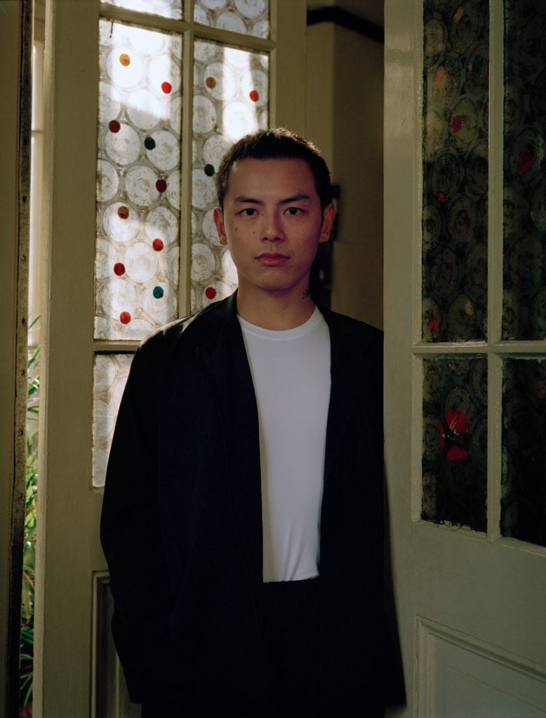 Portrait of an East Asian man in white tee shirt and a black jacket.