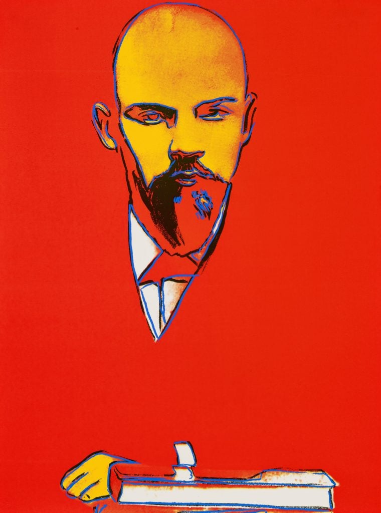 A color screenprint by Andy Warhol titled "Red Lenin" from 1987, featuring a stylized portrait of Lenin against a vibrant red background. The depiction uses bold, contrasting colors with Lenin's face rendered in yellow and outlined in blue, emphasizing his stern expression and iconic beard.