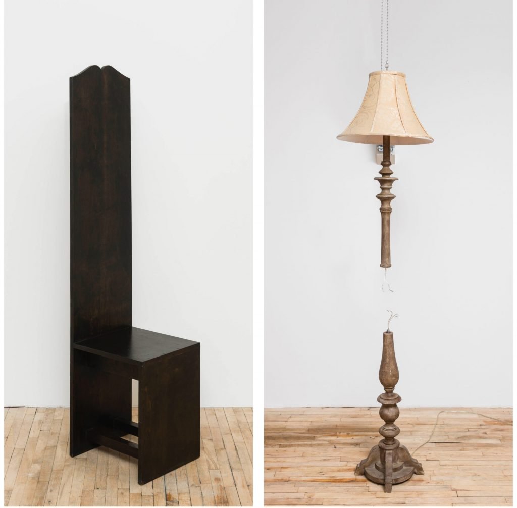 a gallery displays a black chair with a very long back and an old-fashioned standing lamp with a detached center