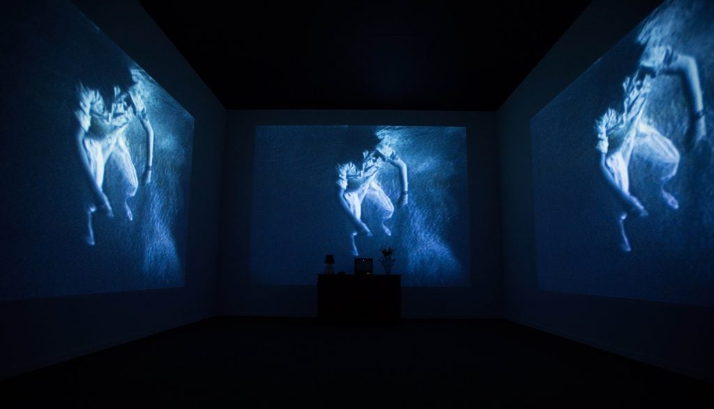 a room with three images of someone floating in blue water on the walls, its dark