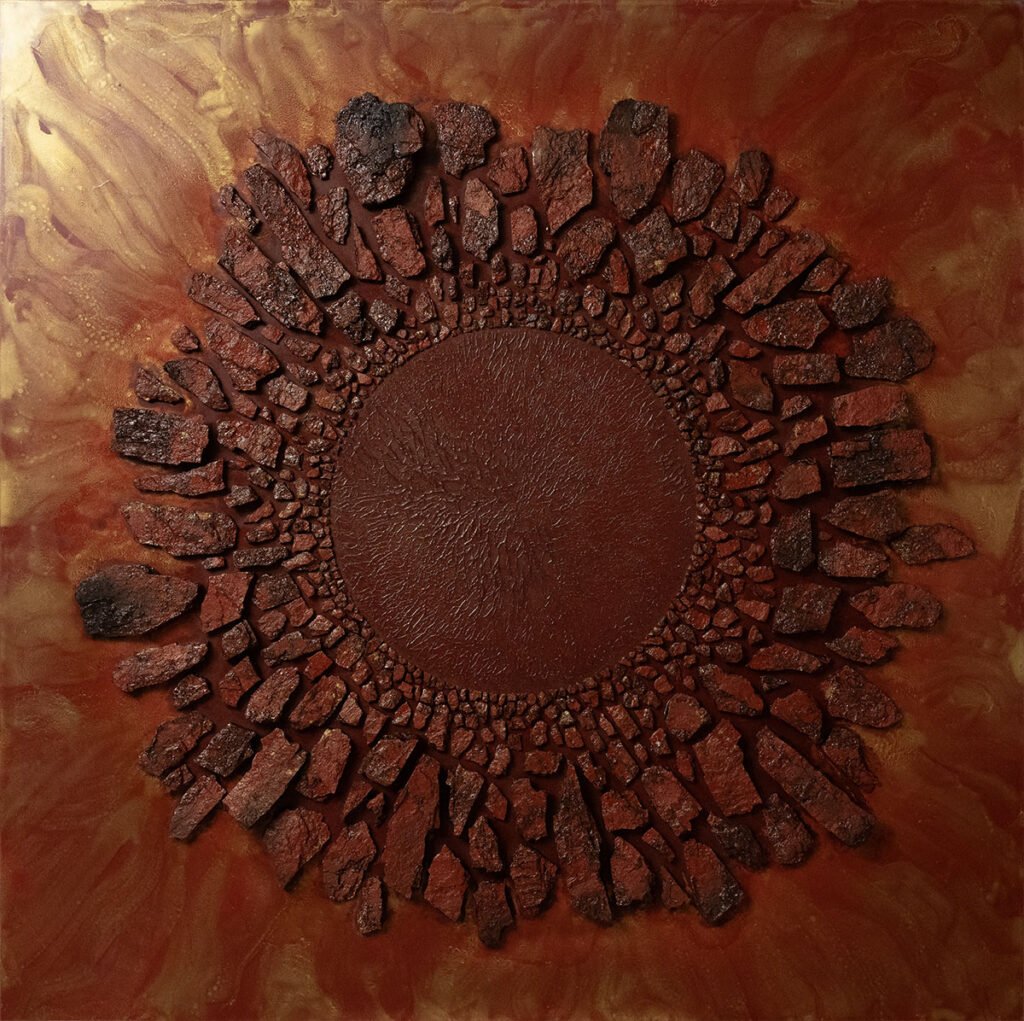 An abstract artwork featuring a circular, textured pattern in shades of reddish-brown, resembling molten or rusted iron, with radiating fragments and a central smooth area.