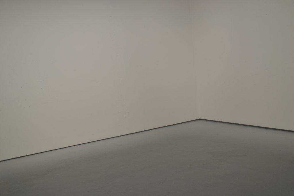 An empty space with two white walls is seen in a photograph.