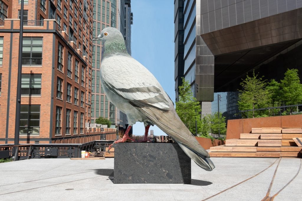 A rendering of Iván Argote's sculpture Dinosaur, a giant pigeon, on the High Line Plinth, with Manhattan office buildings behind it.