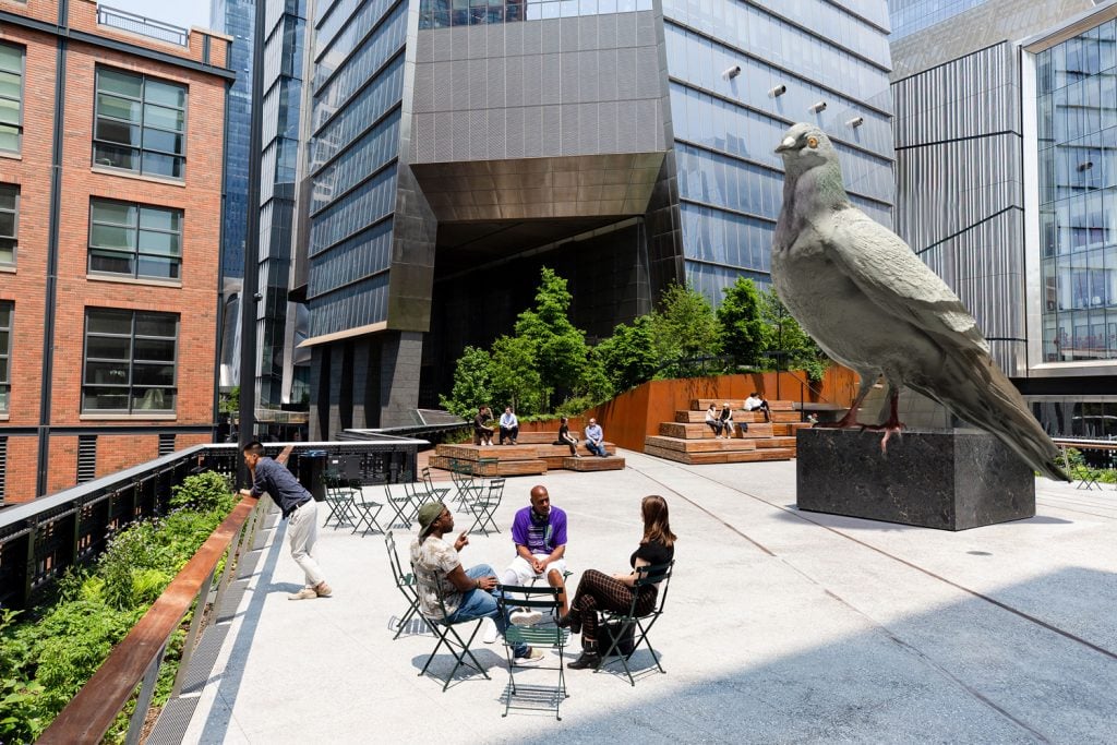 A rendering of Iván Argote's sculpture Dinosaur, a giant pigeon, on the High Line Plinth, with a Manhattan office building behind it.