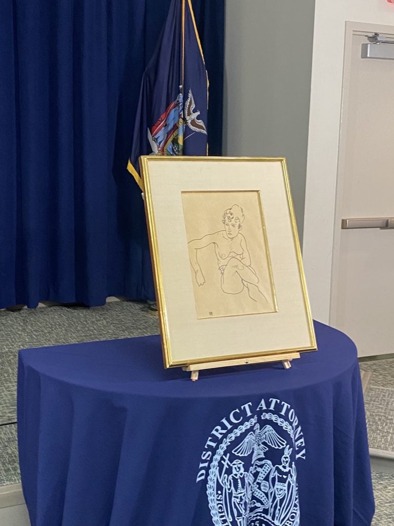 an image of the framed drawing on a table at the conference to announce the return