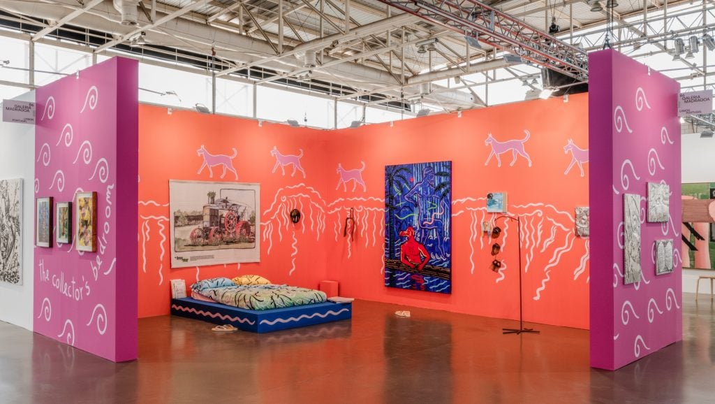 a large structure in an interior space that has orange and pink walls and a double bed in the middle with art on the walls