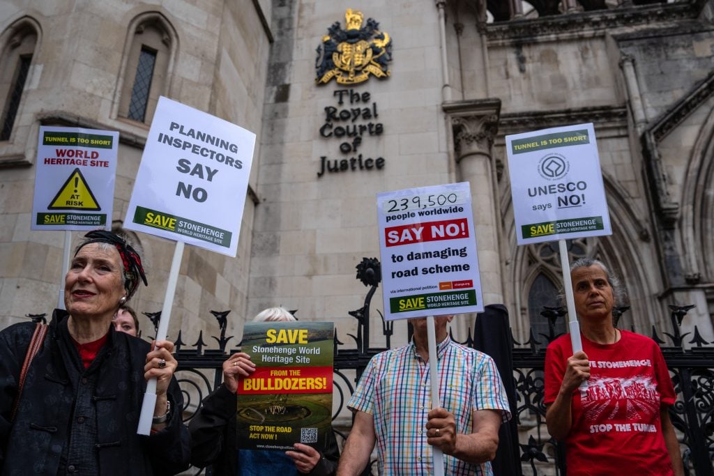 protestors hold signs outside of a courthouse in london