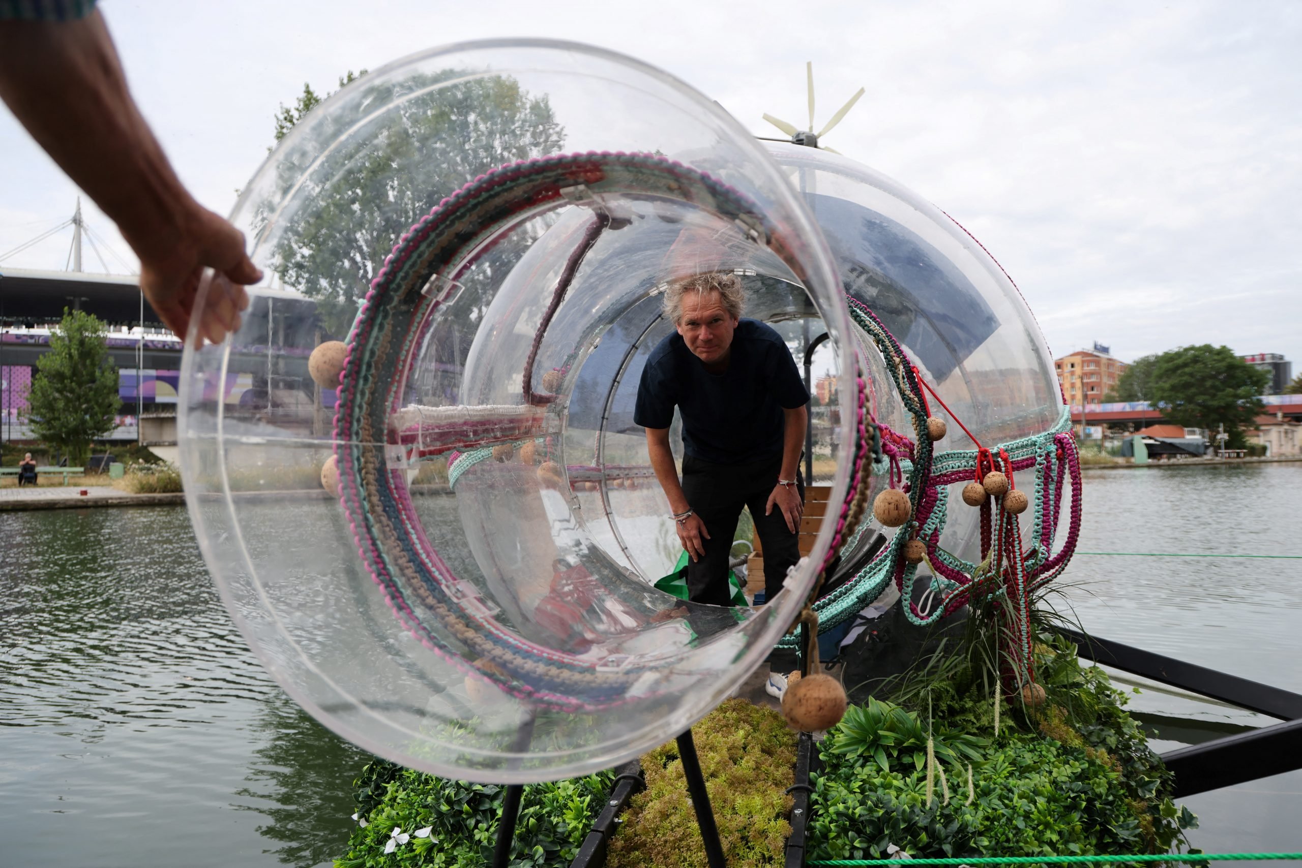 a giant bottle floats on a river with a man inside