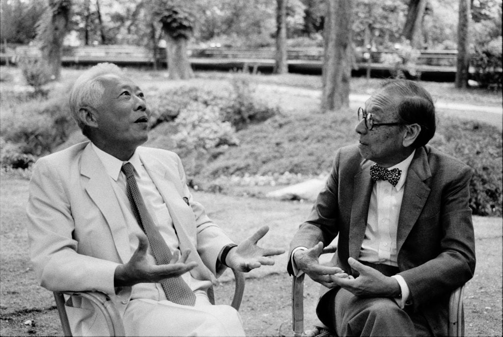 Two Asian men sitting next to each other talking