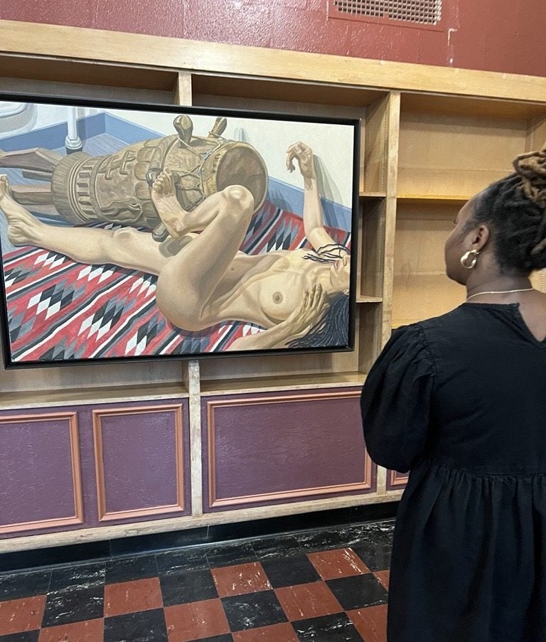 a black woman beholds a painting of a nude white woman on the floor