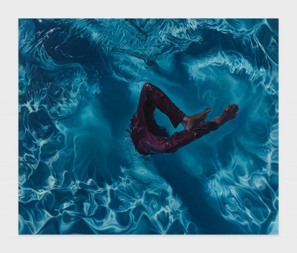 The legs of a black person are seen entering a pool of blue water