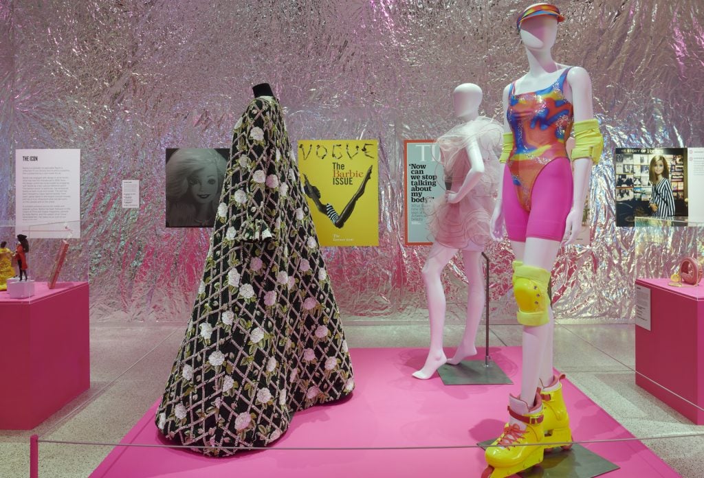 a gallery with a pink floor and silver foil walls features mannequins in various fashions