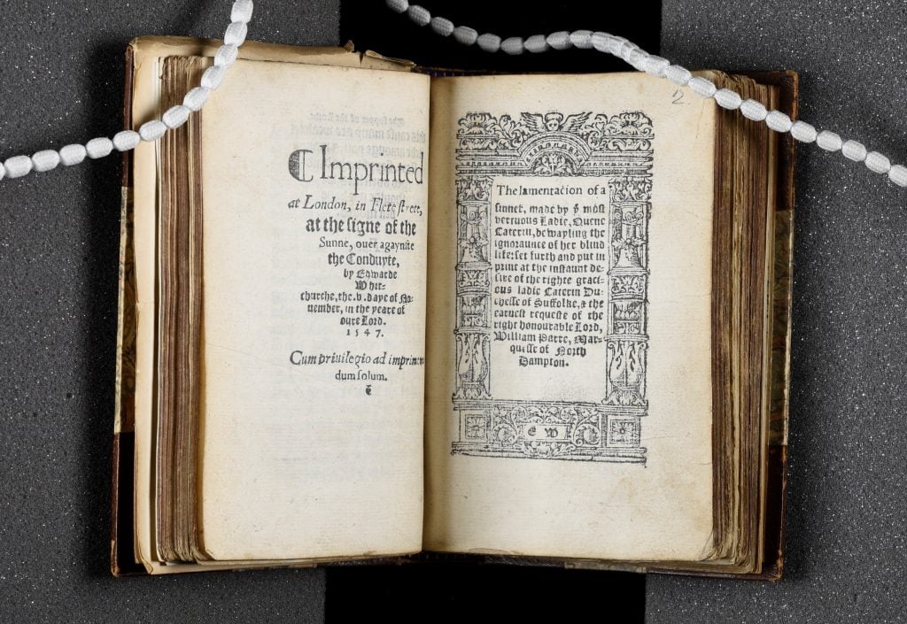 a very old-fashioned Medieval book is seen open on a page of text