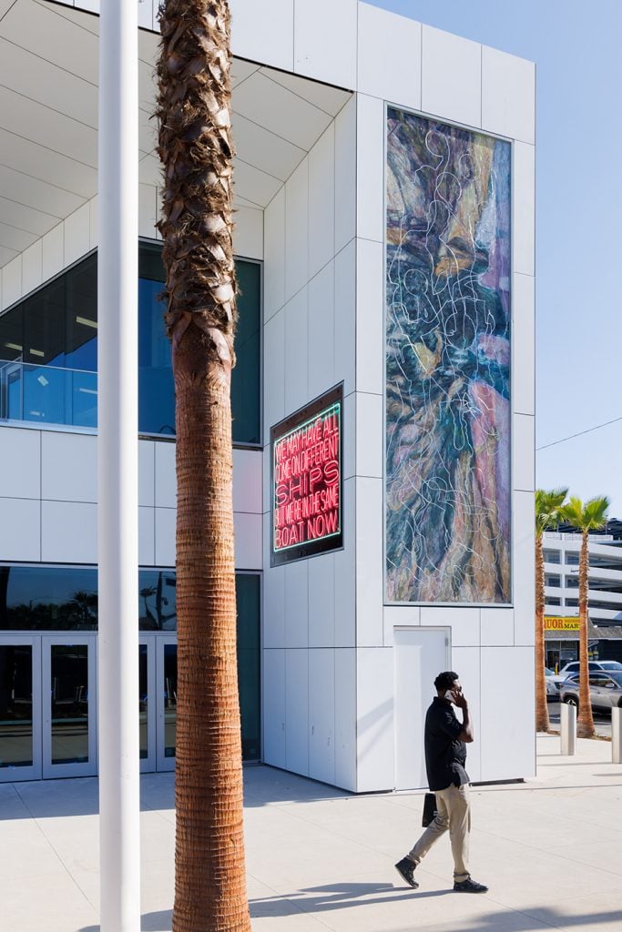 A vibrant mosaic on the side of a white building, depicting various cultural and festive scenes, with people, musical instruments, and colorful elements.