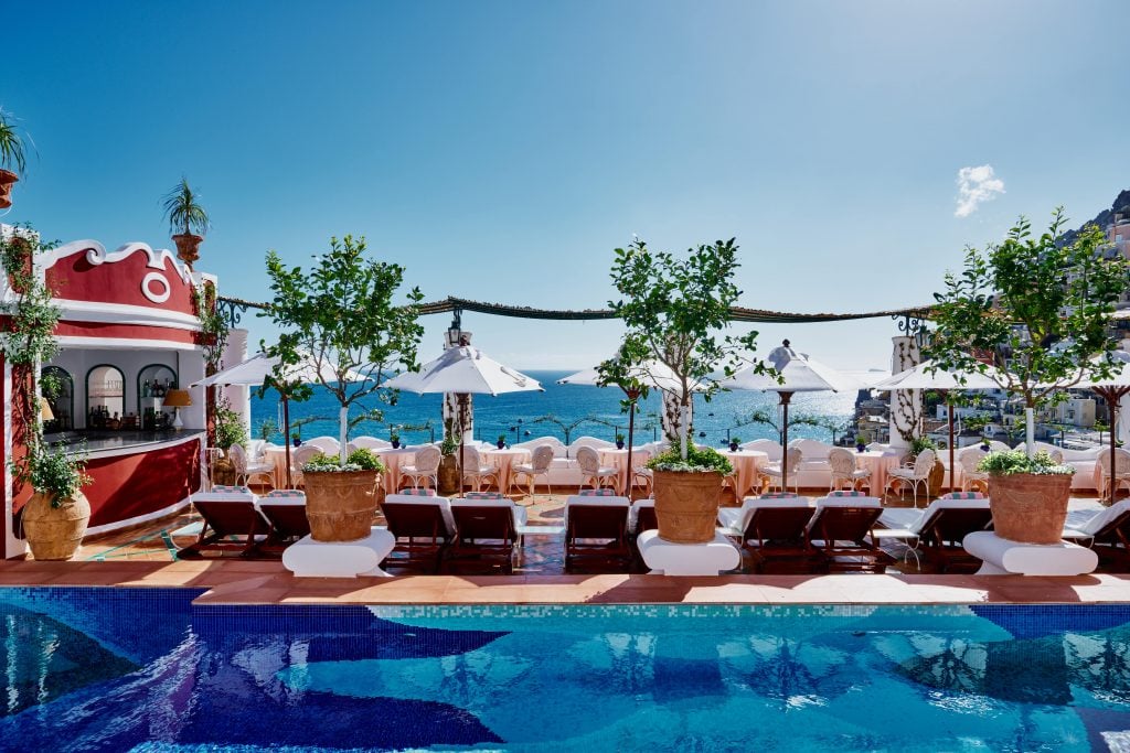 a tiled mosaic pool is set against a Mediterranean Sea backdrop at a luxury hotel