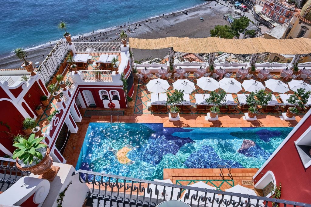 a tiled mosaic pool is set against a Mediterranean Sea backdrop at a luxury hotel 