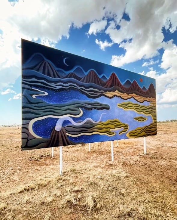 a billboard with a blue landscape instilled in a desert