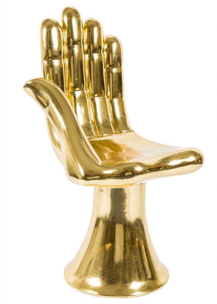 a chair is shaped like a golden hand 