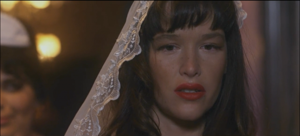 a film still of the actress Paz de la Huerta in red lipstick and a veil 