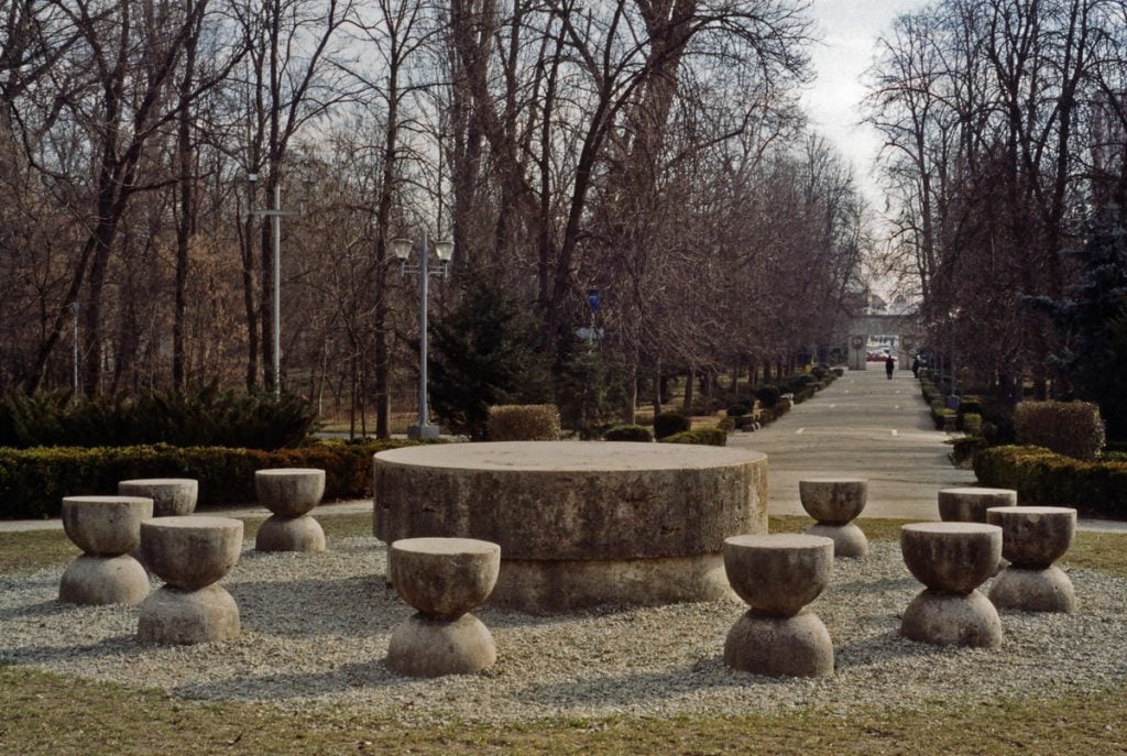 a ring of travertine seats stand around a circular central table. 
