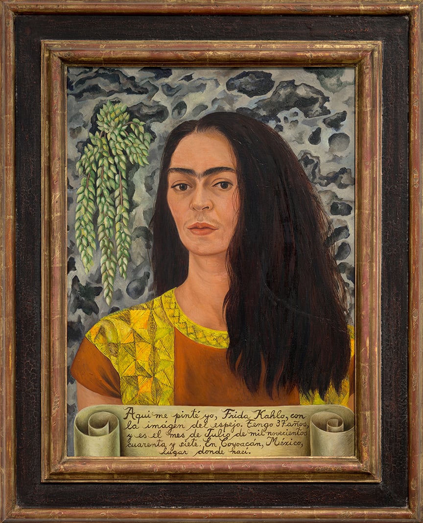 a painting of a woman with loose, long brown hair. The woman's expression is pensive and she wears a yellow and burnt red top in a indigenous Mexican style. Behind her is an abstract gray and black background.