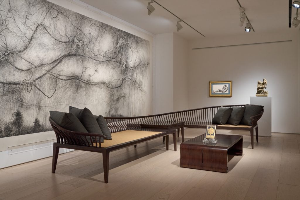 A long designer bench in a room next to a huge painting on the wall