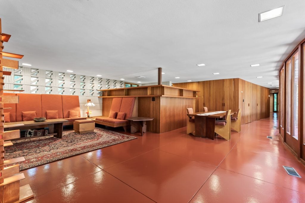 由弗兰克·劳埃德·赖特设计的现代室内设计，采用木质镶板，搭配用餐区和红色地板