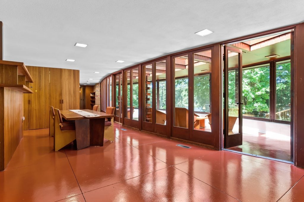 a modern interior by frank Lloyd Wright featuring a red floor and curved windows