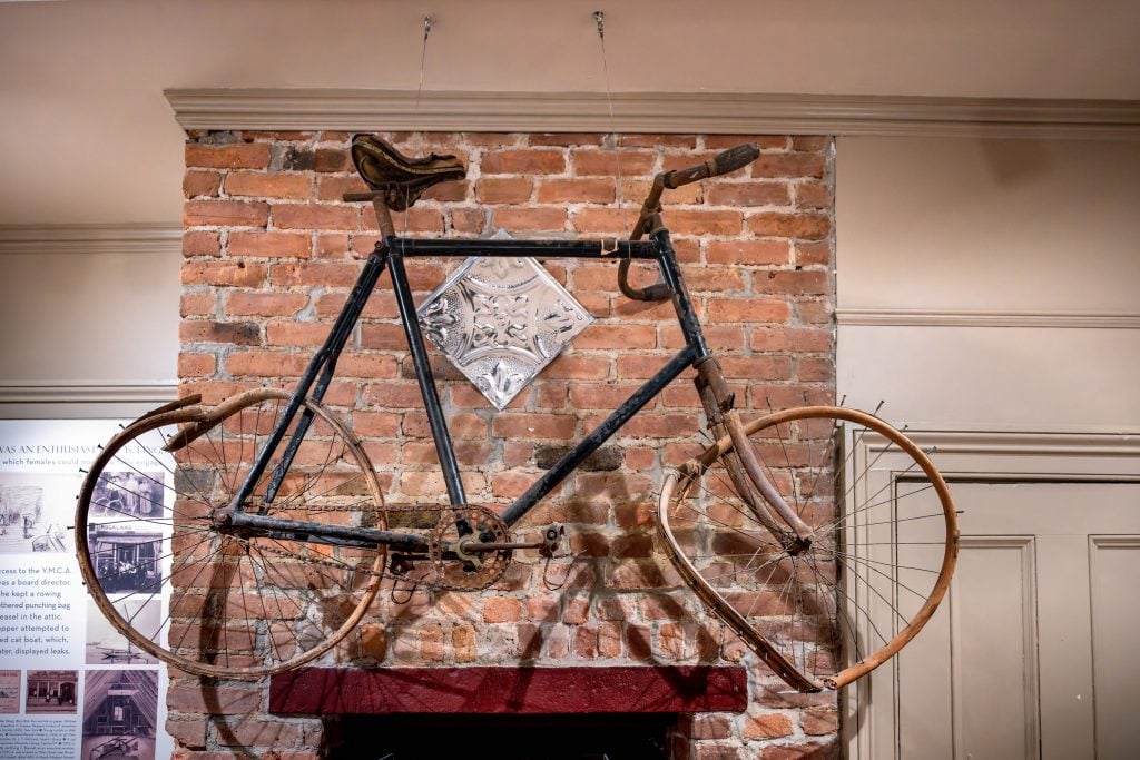 an antique bike with wooden tires mounted onto a brick wall
