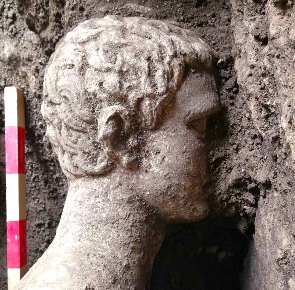 a marble head of a man appears partially embedded in some spoil