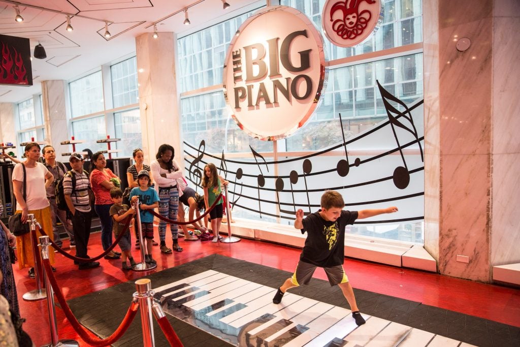 A child jumping over a large piano keyboard designed by Remo Saraceni