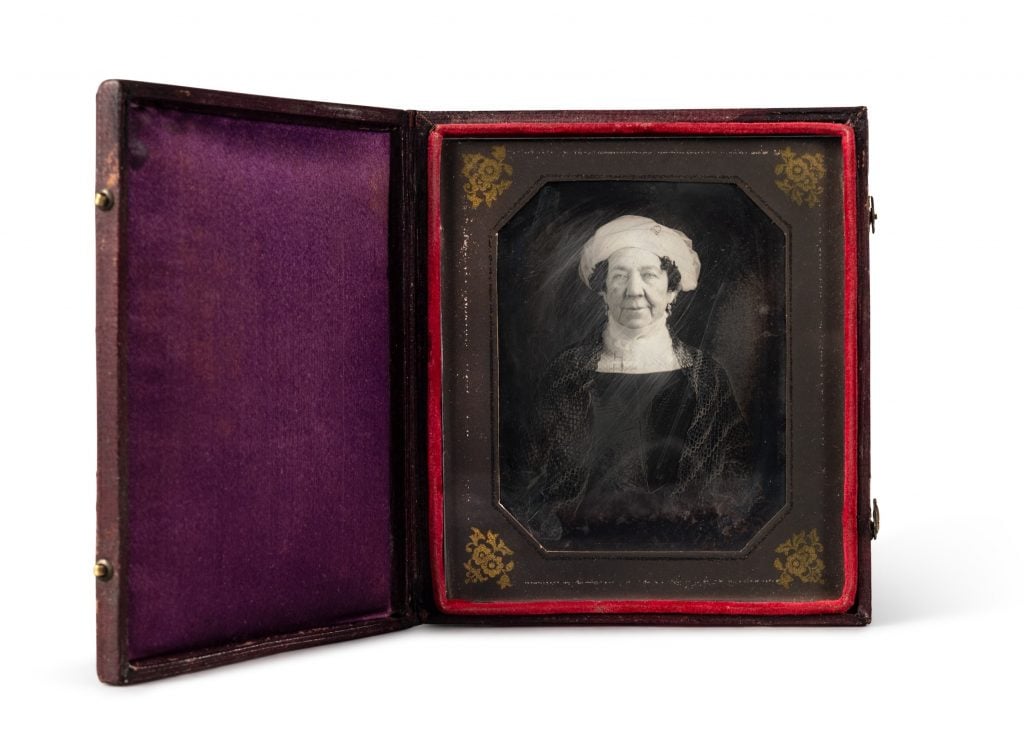 An old-fashioned photograph in a leather folding case, showing a woman in 19th-century clothing