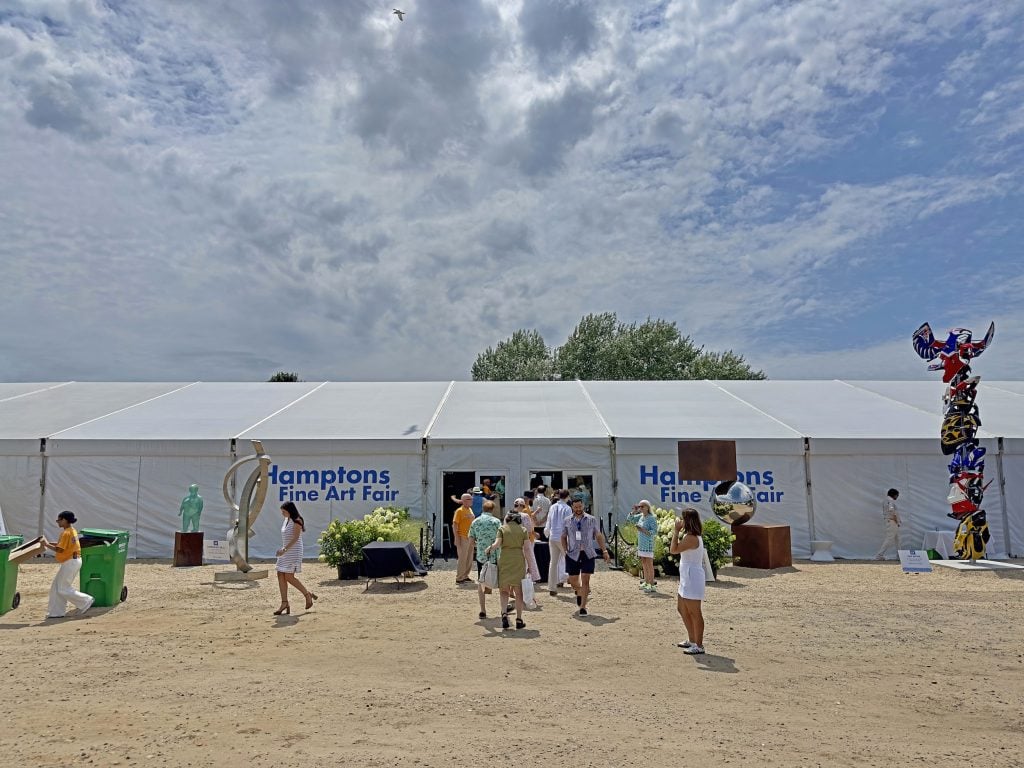 Exterior of the Hamptons Fine Art Fair tent with several large-scale sculptures installed outside and a handful of visitors approaching the entrance.