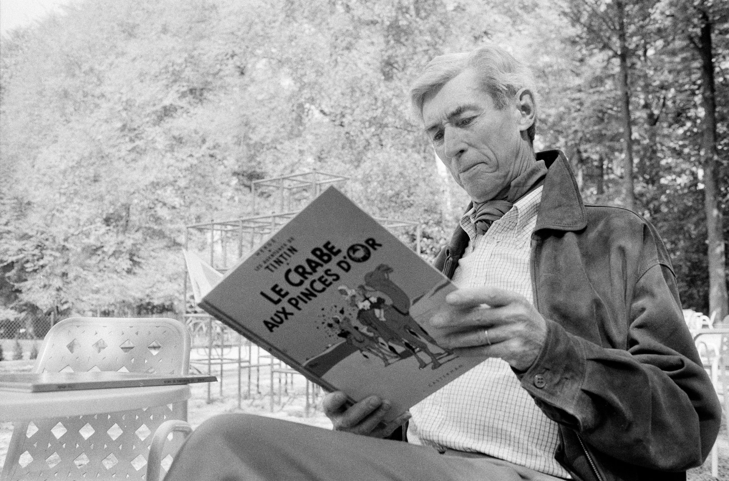 Cartoonist Herge reading a Tintin comic outdoors