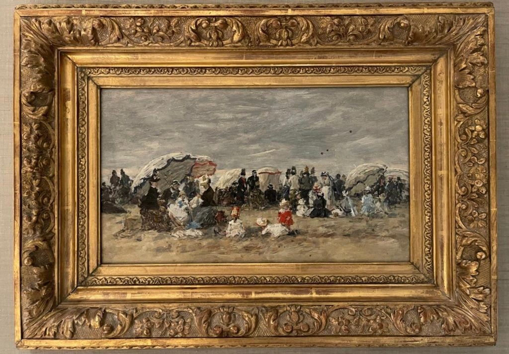 an Impressionist painting in a gilded frame shows a beach scene