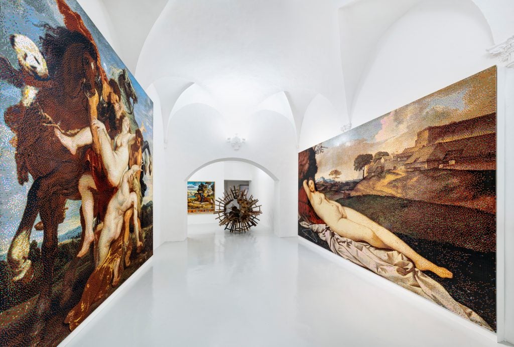 Installation view of Ai Weiwei exhibition with two oversized and distorted images of Old Master paintings on either wall, and on the far end of the gallery two more paintings behind a large-scale sculpture resembling a virus made out of wooden stools.