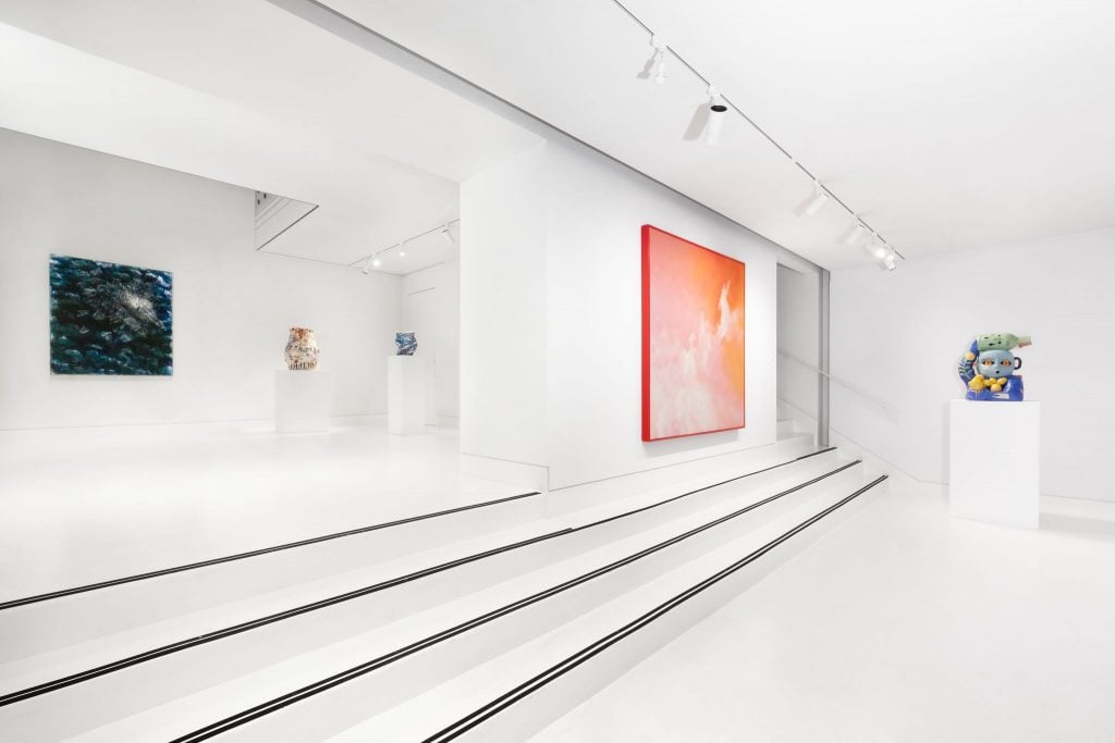 Installation view in white cube gallery space with four shallow steps and two paintings with three sculptures on white pedestals.