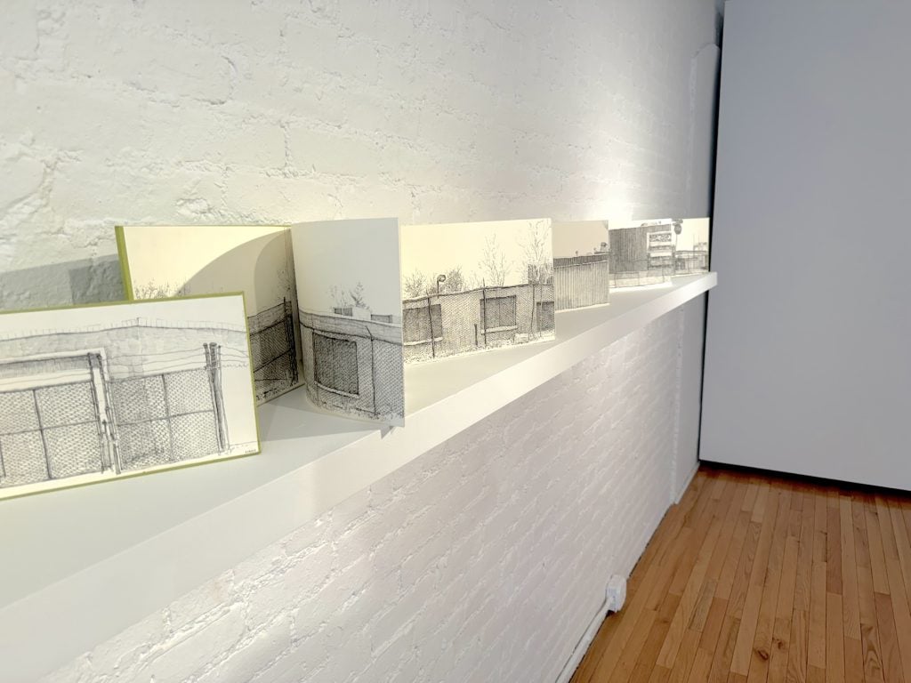 An accordion-fold drawing of an urban landscape on display in a gallery