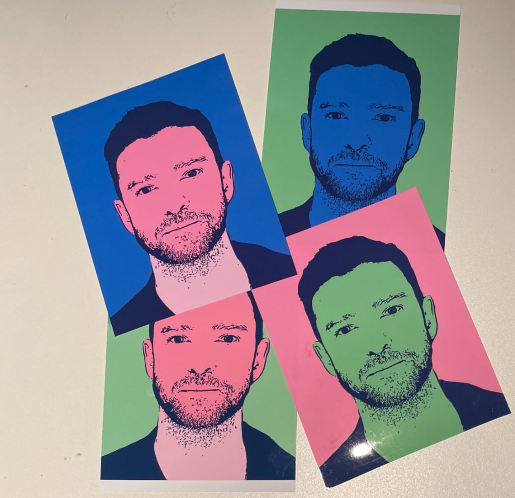 Four artworks based on a mugshot of Justin Timberlake rendered in the style of an Andy Warhol silk screen lying on a table slightly overlapping. There are four different color versions, in shades of pink, green, and blue. 