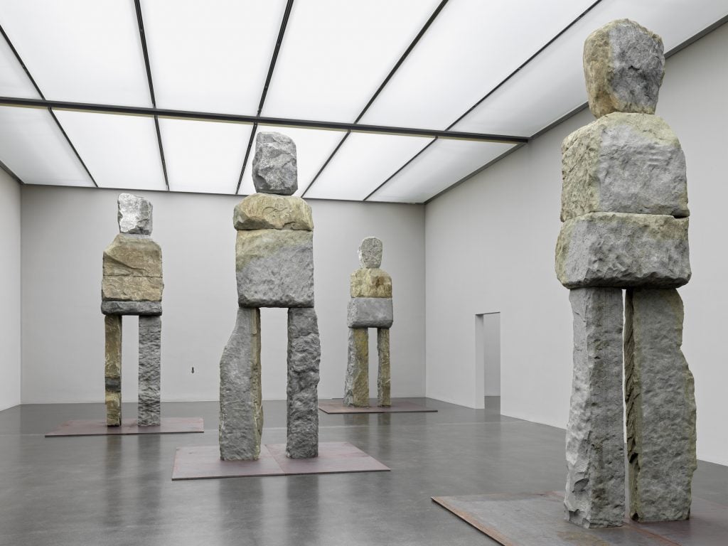 five stone figures in a gallery