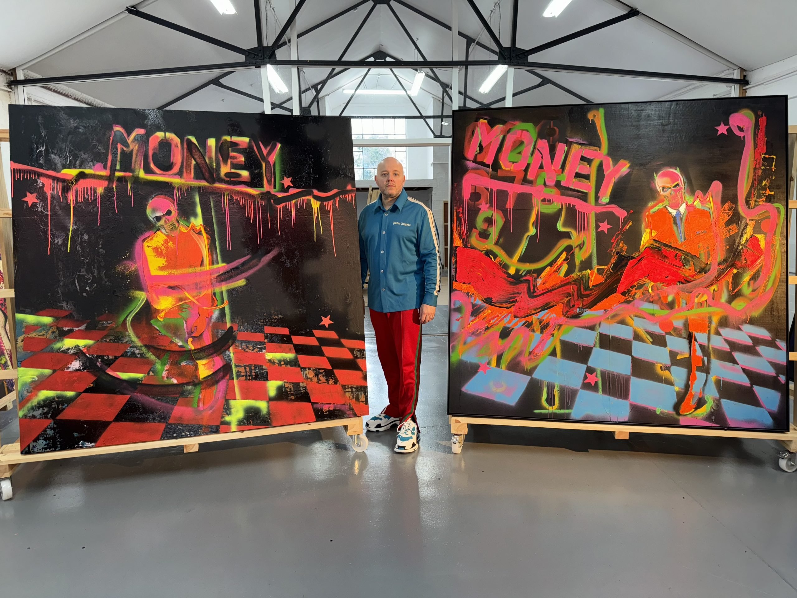 Artist Lincoln Townley standing between two of his large-scale semi-abstract paintings inside a large studio space.