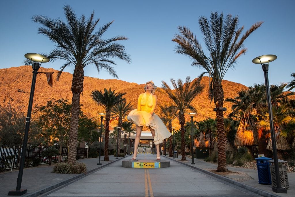 A giant state of Marilyn Monroe stands in a sunlit California landscape