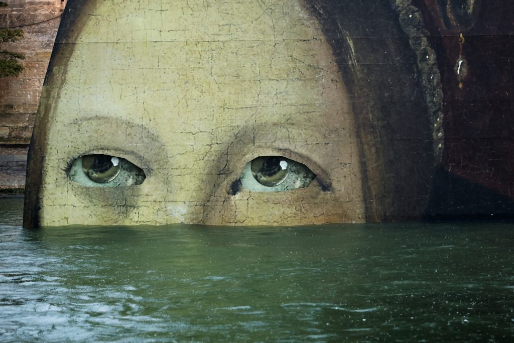 Close up of a large cardboard reproduction of a portrait submerged in water